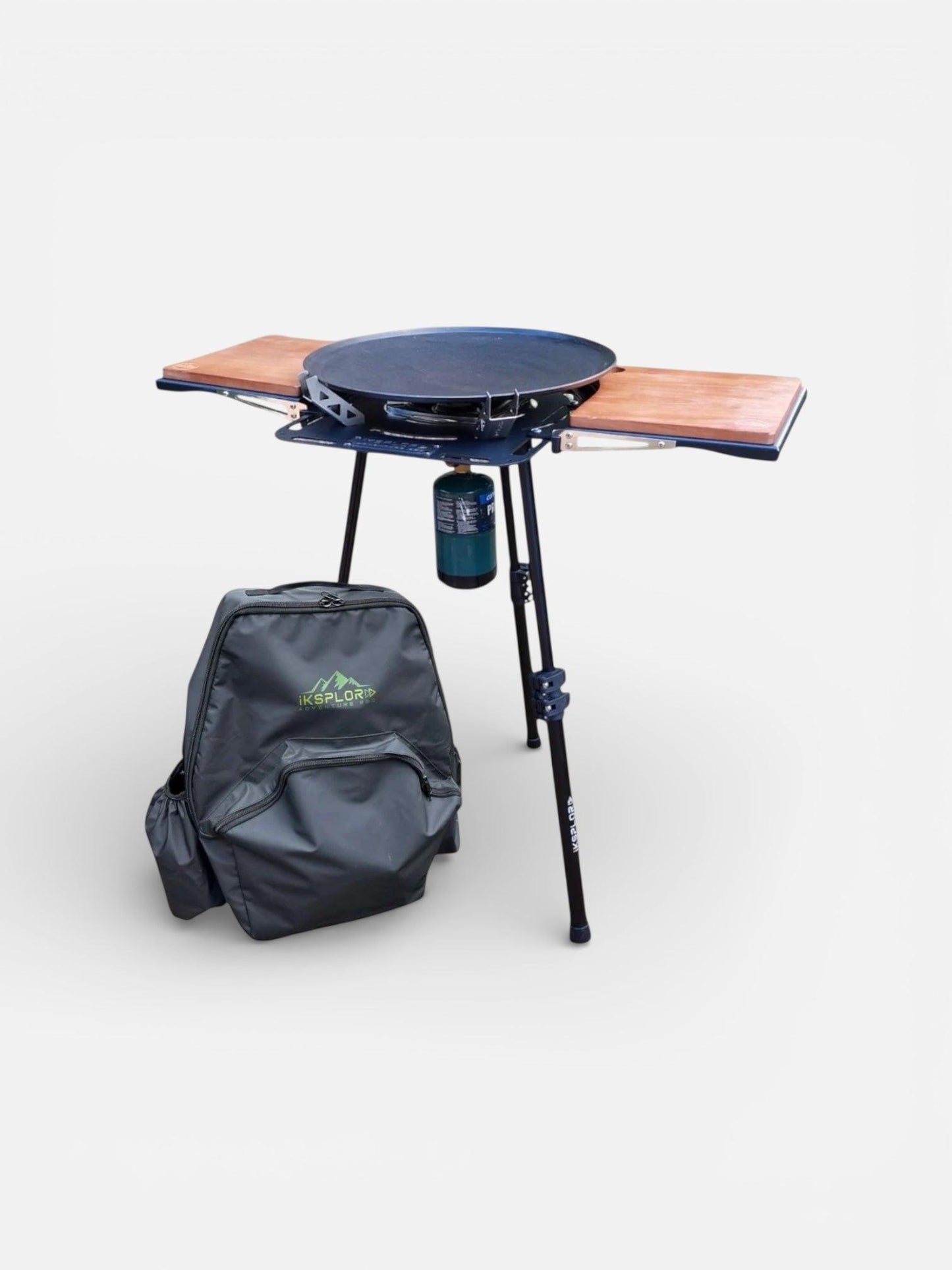 Portable camping bbq with wooden prepboards located on aluminium side table and backpack